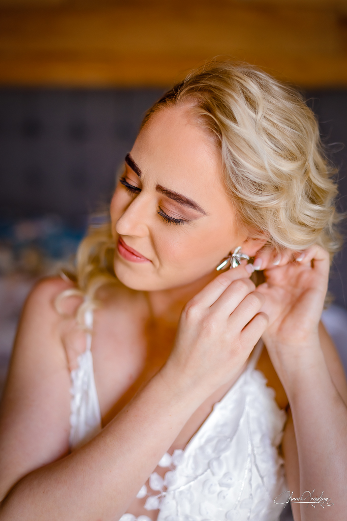 Bride in a satin robe, feeling comfortable on camera on her wedding day while getting ready.